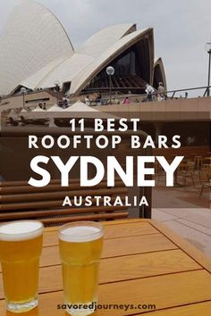 two beers sitting on top of a wooden table in front of a building with the words rooftop bars sydney australia