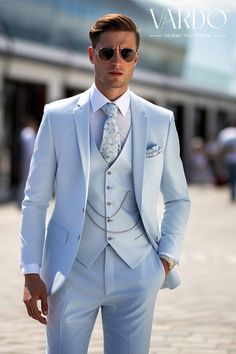 a man in a white suit and sunglasses standing on a brick walkway with his hands in his pockets