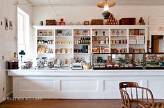 the inside of a store with many items on shelves and chairs in front of it