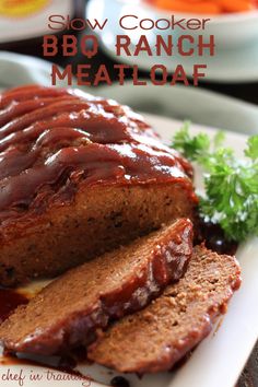 sliced meatloaf with sauce and garnish on white platter next to parsley