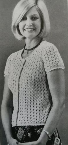 an old black and white photo of a woman with her hands in her pockets smiling