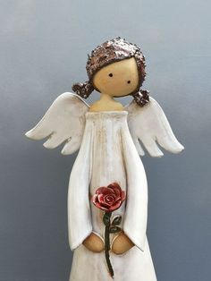 an angel figurine with a rose in its hand and wings on it's back