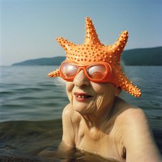 an older woman wearing goggles and a starfish hat in the water at the beach