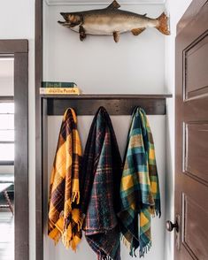 two fish mounted to the wall next to towels hanging from hooks on a coat rack