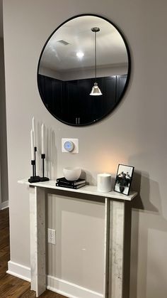 a mirror is hanging on the wall above a console table with candles and other items