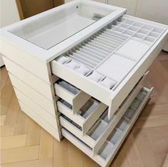 a white cabinet with drawers on top of it in the middle of a wooden floor