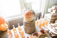 a table topped with lots of food and drinks next to a cake on top of a wooden barrel