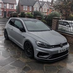 a silver car parked on top of a cobblestone road in front of houses