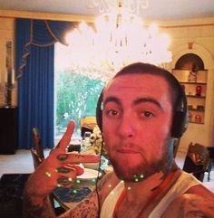 a man with headphones on taking a selfie in front of a chandelier