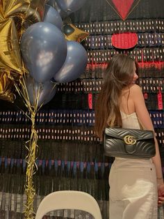 a woman standing in front of balloons and streamers with her purse on her shoulder