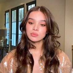 a woman with long brown hair is looking at the camera while wearing a sequin top