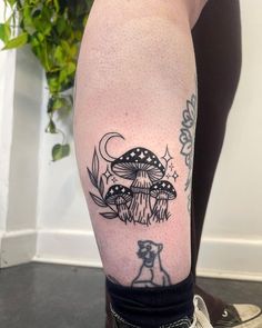 a woman's leg with tattoos on her legs and an image of mushrooms in the background