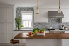 a kitchen with white cabinets and wooden counter tops, along with a bowl of vegetables on the island