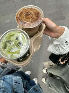 two people are holding their drinks in plastic cups