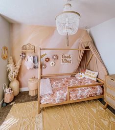 a bedroom with pink walls and gold bedding, white chandelier hanging from the ceiling