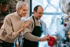 two people standing in front of a stove cooking food on top of a burner