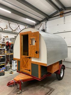 a horse trailer with an open door on the side in a garage next to antlers