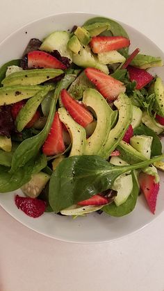 a white plate topped with spinach and strawberries