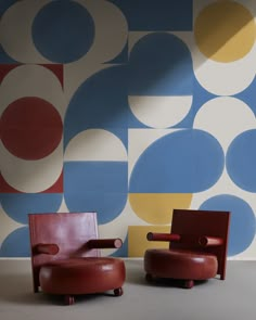 two chairs sitting next to each other in front of a wall with circles on it