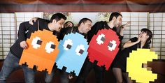 a group of people standing next to each other holding up pacman paper cutouts