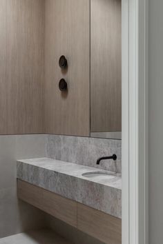 a bathroom with marble counter tops and wooden cabinetry, along with two black faucets