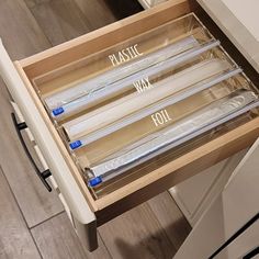 an open drawer with plastic wrap on the bottom and four candles in it that are labeled plastic, wax, and foil