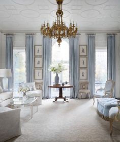 a living room filled with furniture and a chandelier hanging from the ceiling over a table