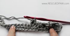 someone crocheting the end of a piece of yarn with a pair of scissors