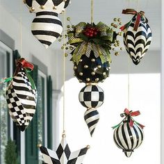 black and white christmas ornaments hanging from a ceiling in front of a house with green shutters