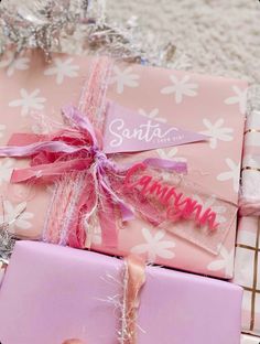 two wrapped presents sitting on top of each other in pink and silver wrapping paper with the word santa written on them