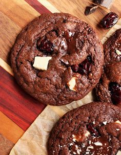 three chocolate cookies with cranberries and cheese on top