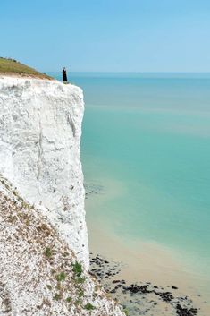 a person standing on top of a white cliff near the ocean