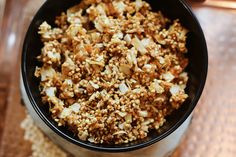 a black bowl filled with granola on top of a wooden table