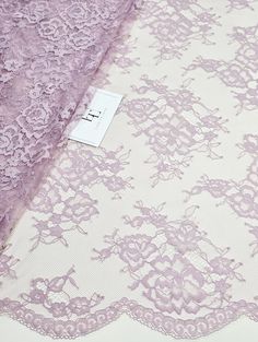 the fabric is purple and has lacy lace on it, along with a white background