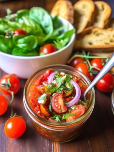 a salad in a jar with tomatoes, onions and bread on the side