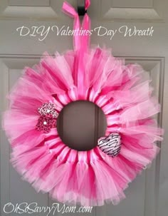 a pink tulle wreath with zebra print and heart decorations hanging on the front door