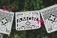 two white paper cutouts with the word mom and flower on them hanging from a tree