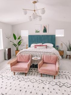 a bed room with a neatly made bed and two pink chairs next to each other