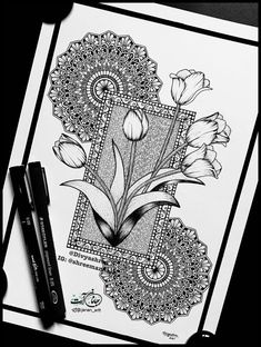 a black and white drawing of tulips on a piece of paper next to a pen