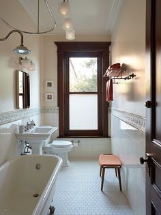 a bathroom with two sinks, a toilet and a bathtub in front of a window