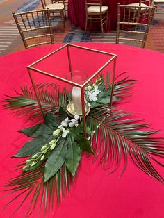 an arrangement of flowers and greenery on a red table cloth at a wedding reception