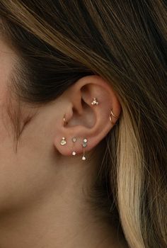 a woman wearing gold ear piercings with small white stones