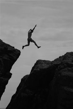 a man jumping off the edge of a cliff into the ocean