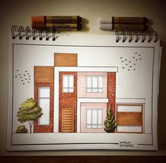 a drawing of a house with trees and birds on the roof, next to two pencils