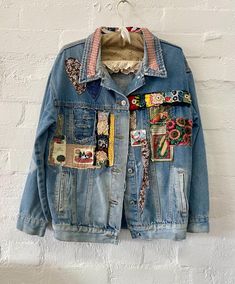 a denim jacket with patches and buttons hanging on a wall