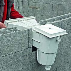 a man standing next to a brick wall with a white toilet attached to the side