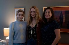 three women standing next to each other in a living room