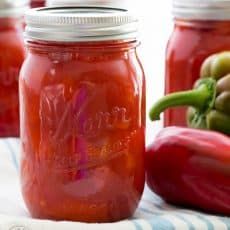 three jars filled with red liquid sitting on top of a white and blue table cloth