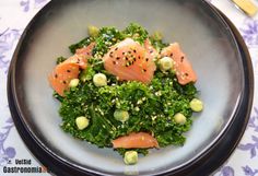 a plate filled with vegetables and fish on top of a blue table cloth next to utensils