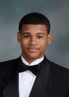 a young boy in a tuxedo poses for a photo wearing a bow tie